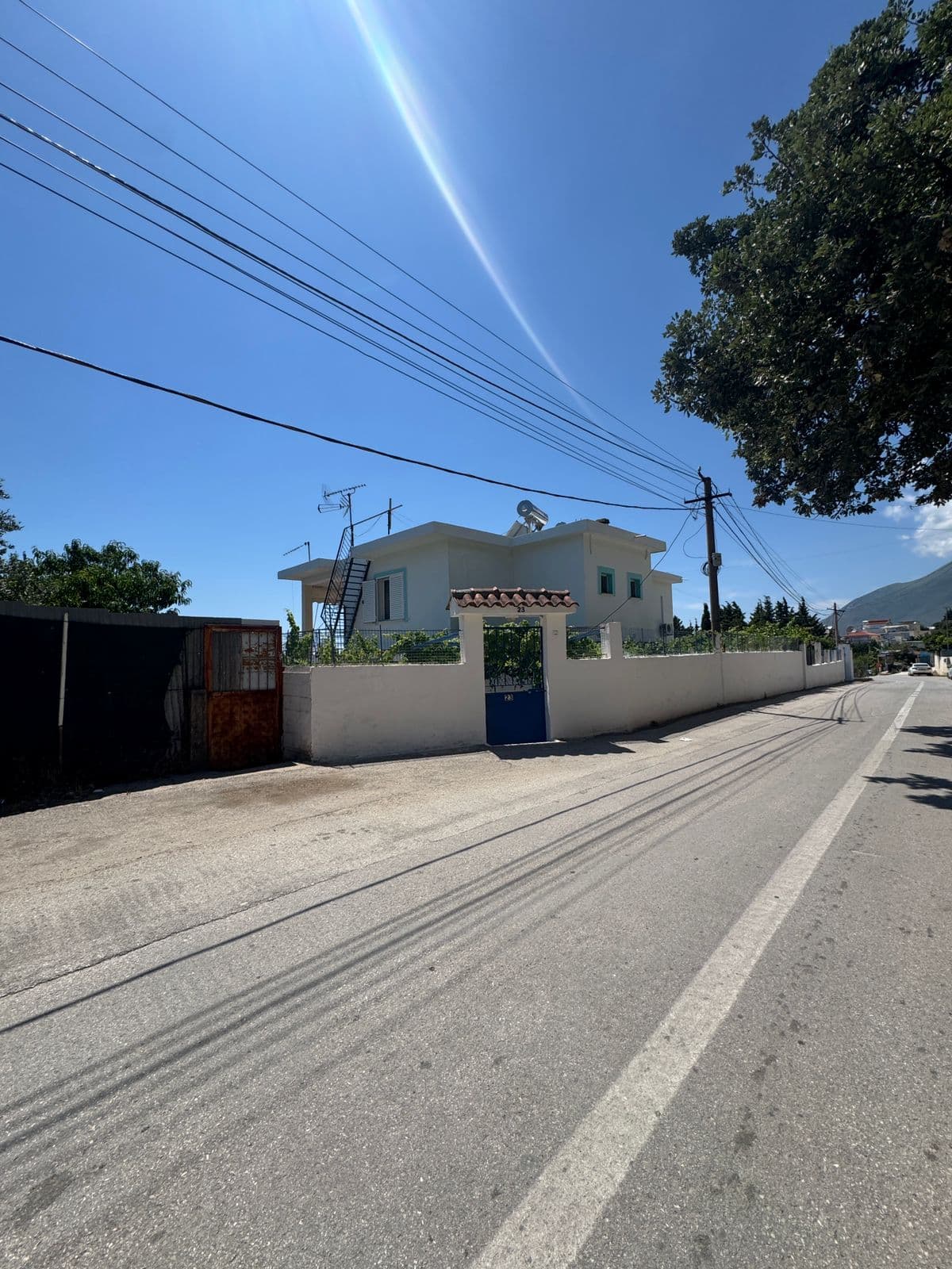 Kristaqi Rooms seen from the road — white building with blue gate